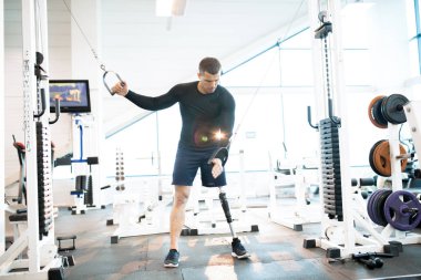 Protez bacak modern spor salonunda makinasıyla dışarı çalışma ile yakışıklı kaslı adam portresi tam uzunlukta