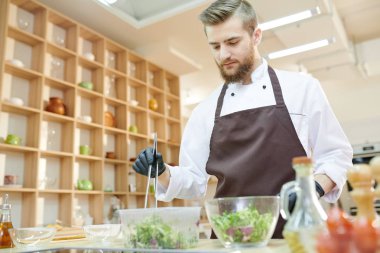 Modern profesyonel şef modern Restoran mutfağında, kopya alanı çalışırken yeşil salata malzemeleri karıştırma kadar bel