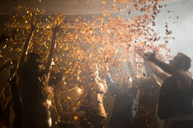 Neşeli grup arkadaşıyla gece kulübü, altın konfeti havada uçan dışarı asılı iken modaya uygun müzik dans