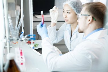 Laboratuvar masa başında oturan ve beslenme özellikleri test tüpü içinde çözümün analiz genç bilim adamları kırpma yan görünüm
