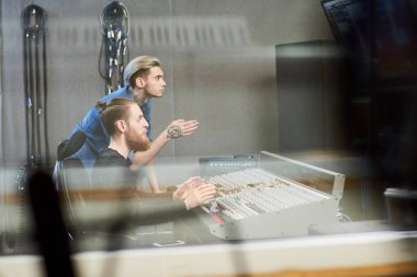 Cam stüdyo kayıt ve şarkıcı için söz müzik konsolu oturan yaratıcı operatörlerin yan görünümü.