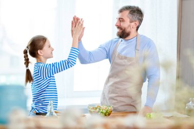 Olgun portre birlikte evde mutfakta yemek yaparken küçük kızı için yüksek beş veren adam sakallı