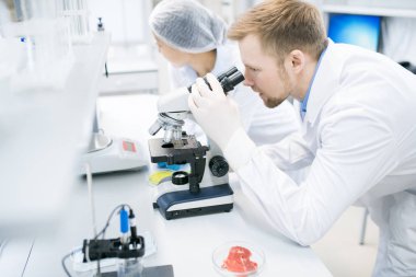 Yan görünümü mikroskobu tıbbi laboratuvar araştırma yaparken seyir modern genç bilim adamı portresi
