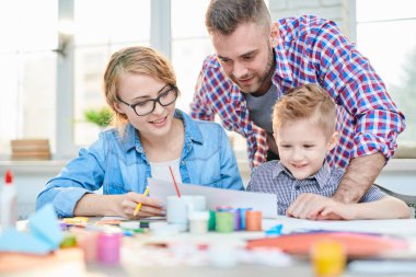 Sevgi dolu aile üç Pazar evde harcama: onlar birlikte modern oturma odası ve renkli resimle çizim guaş toplandı