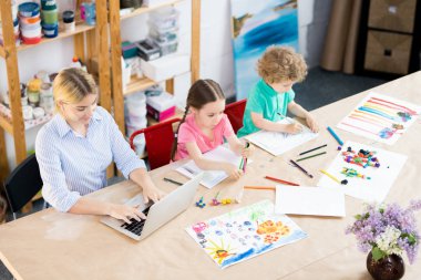 Çocuk sanat derste dizüstü bilgisayarda yazarak öğretmen ile çizmek için öğrenme