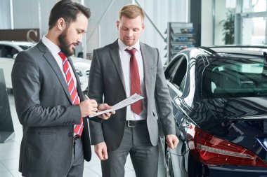 Profesyonel satıcı adam araba salonda sözleşmenin koşulları açıklama