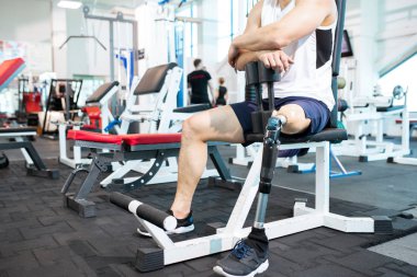 Modern spor salonu, kopya alanı mola egzersiz sırasında bankta oturan dinlenme tanınmaz amputee sporcu düşük bölüm portresi