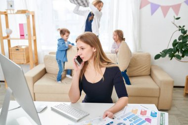Bel öğe, dikey, Genç ve güzel serbest işçinin smartphone, küçük çocukları yastık kavgası, iç oturma odası arka plan üzerinde sarılı kullanırken istemci ile sipariş ayrıntıları tartışıyor