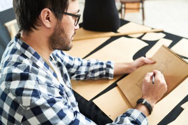 Casual adam Studio masada oturan Notepad için elbise tasarımı oluşturma bardaklarda yan görünüm. 