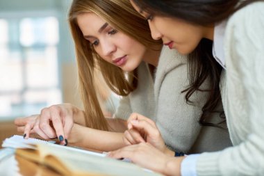 Modern Koleji Konferans salonunda masada oturan notlar okuyan iki güzel kız portresi