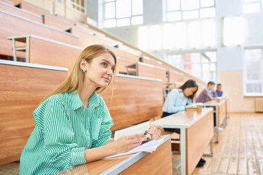 Uluslararası Grup modern üniversite, güzel sarışın kadın s ön planda odaklanmak konferans salonunda ayrı masalarda oturan insan