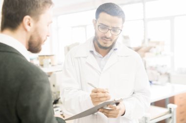 Genç Arap Müfettiş sakallı girişimci modern Fabrikası gece turunu vererek sırasında gerekli notlar alarak arka plan bulanık