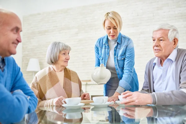 Mujer Sirviendo Para Pacientes Mayores Casa Asistida Sentada Mesa Charlando — Foto de Stock