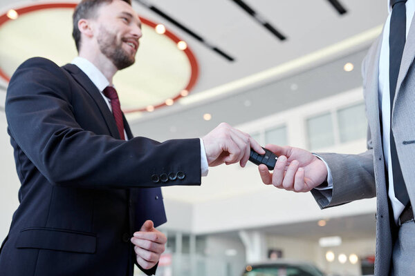 Close-up of dealer giving a key from new car to the owner