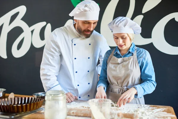 Chef teaching his assistant to bake the pie