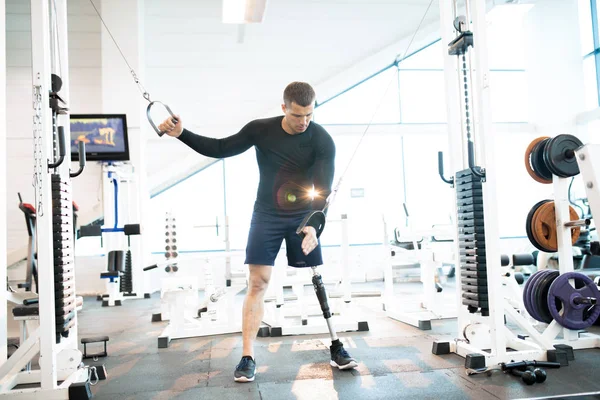 Protez bacak modern spor salonunda makinasıyla dışarı çalışma ile yakışıklı kaslı adam portresi tam uzunlukta