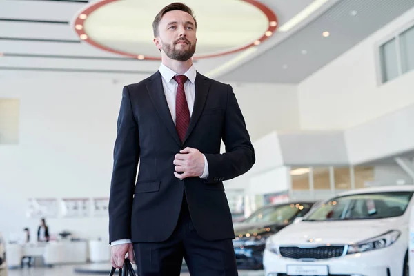 Σοβαρές Νεαρός Επιχειρηματίας Στο Κοστούμι Στέκεται Στο Εκθετήριο Αυτοκινήτων Θέλει — Φωτογραφία Αρχείου