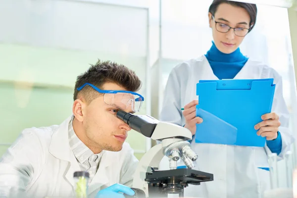 Knappe Jonge Wetenschapper Dragen Van Veiligheidsbril Witte Vacht Zoek Microscoop — Stockfoto