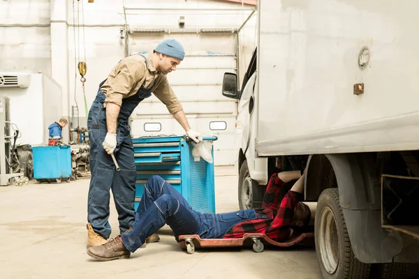 Young Male Auto Mechanic Giving Tools His Colleague Lying Creeper — Stock Photo, Image