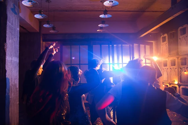 昏暗的夜总会内部 男女在一起庆祝新年的同时 随着时尚的音乐跳舞的剪影 — 图库照片