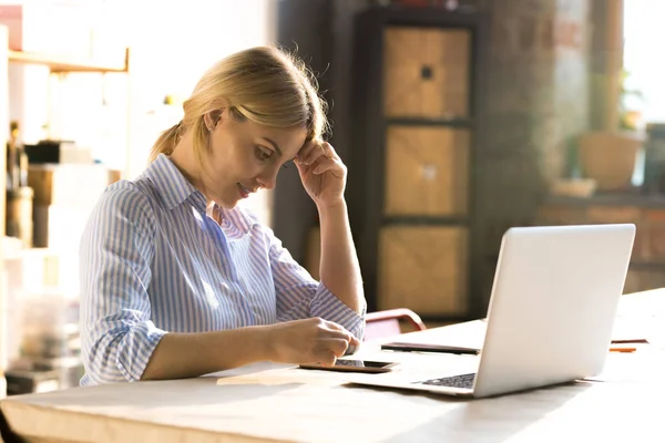 Mujer Rubia Joven Sentada Mesa Usando Teléfono Inteligente Mientras Trabaja — Foto de Stock