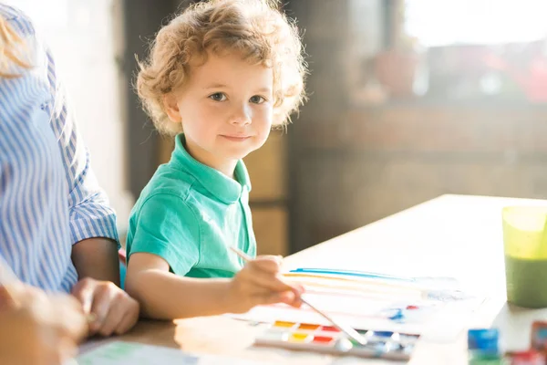 Caliente Retrato Tonificado Lindo Niño Mirando Cámara Mientras Pinta Cuadros — Foto de Stock