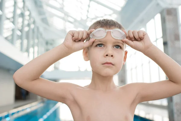 认真确定的男孩寻找距离和准备在游泳池训练 他调整护目镜 — 图库照片