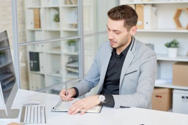Beyin fırtınası sırasında Notlar başlangıç proje üzerinde arka plan üzerinde modern ofis iç alarak kendine güvenen genç Yöneticisi portre çekim