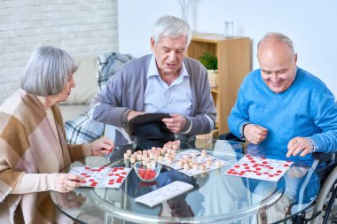 Üst düzey kişi emeklilik ev oturma odasında cam masada oturan loto oyunu oynayan portresi