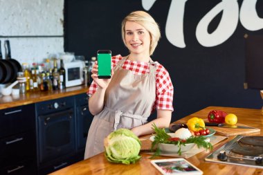Smartphone ile mutfak at duran genç kadın portresi