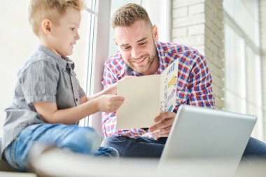 Portre yakışıklı genç adamın oğluyla kenarında oturan ve mutlu bir şekilde gülümseyerek babalar günü için kart okuyucu