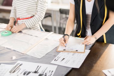 Yüksek açı kırpmak atış skeçler çizim ve özel yapılmış giysiler için desenler moda tasarım proje modern atelier studio birlikte çalışma sırasında yapma iki tanınmaz halde kadın terzi.