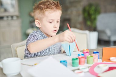 İlkokulda çocuklar masasında otururken pastel renklerle boyama şirin küçük çocuk portresi