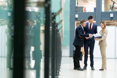 Resmi kıyafeti modern ofis raporda tartışırken kağıtları ile ilgilenen ciddi düşünceli iş arkadaşları