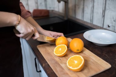 Kırpma adam şık mutfak ve kesme lezzetli Portakal yarısı üzerinde sayaç yakınındaki ayakta. 