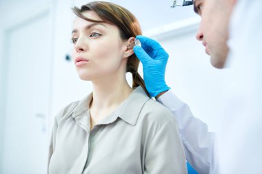 Kulakları incelenmesi ve güzel genç kadın işitme Doktor düşük açılı portresi