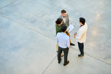Yüksek açı görüntülemek grup projesinde modern ofis binası, kopya alanı tartışırken daire içinde ayakta başarılı genç iş adamları