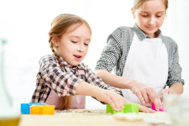 Anneler günü için lezzetli sürpriz yaparken mutfak masası ve kesme kurabiye hamur ürünleri ayakta forma giyen sevimli küçük kız kontrol
