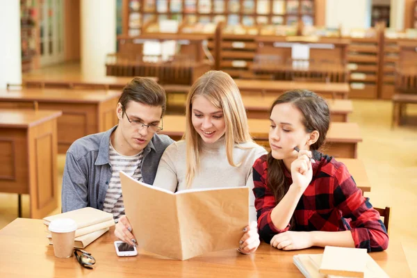 Jovens Estudantes Curiosos Positivos Sentados Mesa Lendo Livros Interessantes Biblioteca — Fotografia de Stock