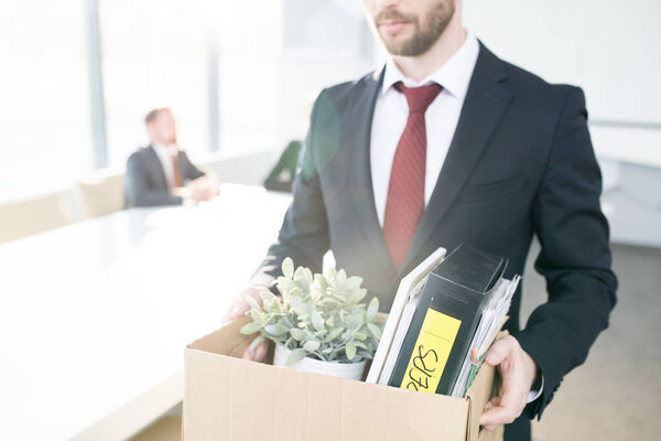 Mid section portrait of handsome businessman holding box of personal belongings  leaving office after quitting job
