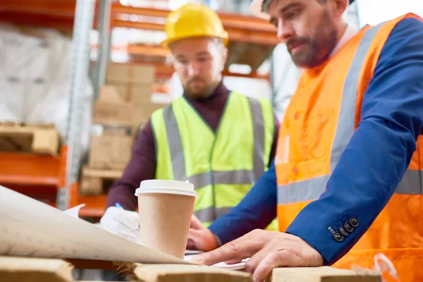 Waist up portrait of two workers studying documentation on site, focus on foreground, copy space