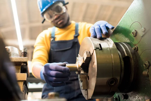 安全ゴーグルと近代的な工場の生産部門で働きながら機器を調整するヘルメットを身に着けている自信を持っているアフリカ系アメリカ人のマシン オペレーター — ストック写真