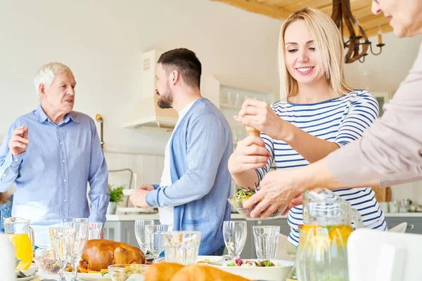 Portrait of happy two generation family preparing dinner together serving table with delicious homemade dishes for holiday  in modern apartment lit by sunlight