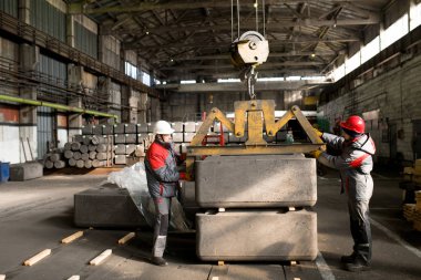 Atölyede vinç kullanırken yükleri hareket ettiren iki fabrika işçisinin tam uzunlukta yan görünüm portresi, kopyalama alanı