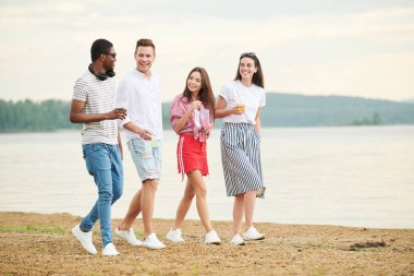 Sahilde yürüyen ve güzel doğayı tartışan çok ırklı gençler