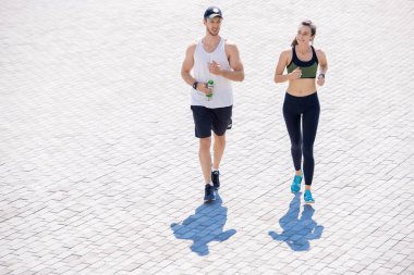 Döşenmiş arka plan üzerinde güneş ışığı açık havada modern genç çift jogging yüksek açı portre, kopya alanı