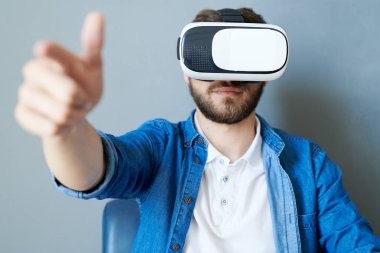 Oyun oynarken veya 360 video izlerken elleri uzanan koltukta oturan Vr dişli giyen modern genç adamın ön görünüm portre, kopya alanı