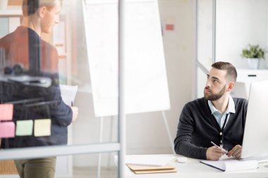İş tartışırken iş arkadaşına bakan sakallı ofis çalışanının portresi, kopya alanı