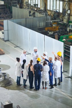 Olgun fabrika yöneticilerinin endüstriyel atölyede toplantı sırasında ajite işçi grubu ile konuşurken yüksek açılı portre, kopya alanı