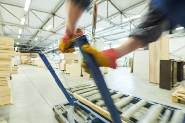 Mobilya fabrikasında silindir konveyörü düzenlerken metal sapı ayarlayan tanınmayan işçinin yakın çekim